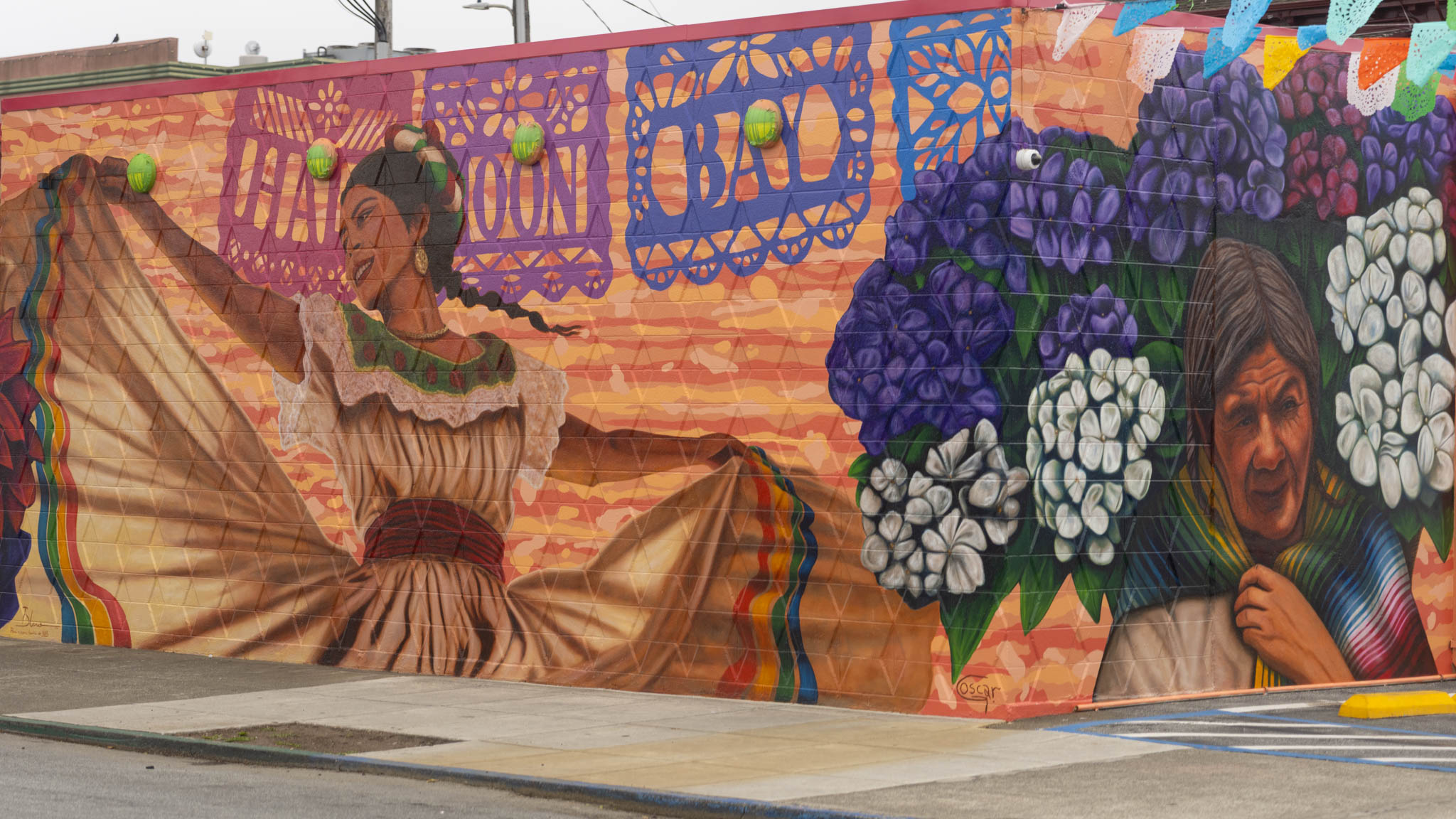 Colorful mural on a wall with two dancers, floral designs, and the words “HALLOWEEN BALL.”