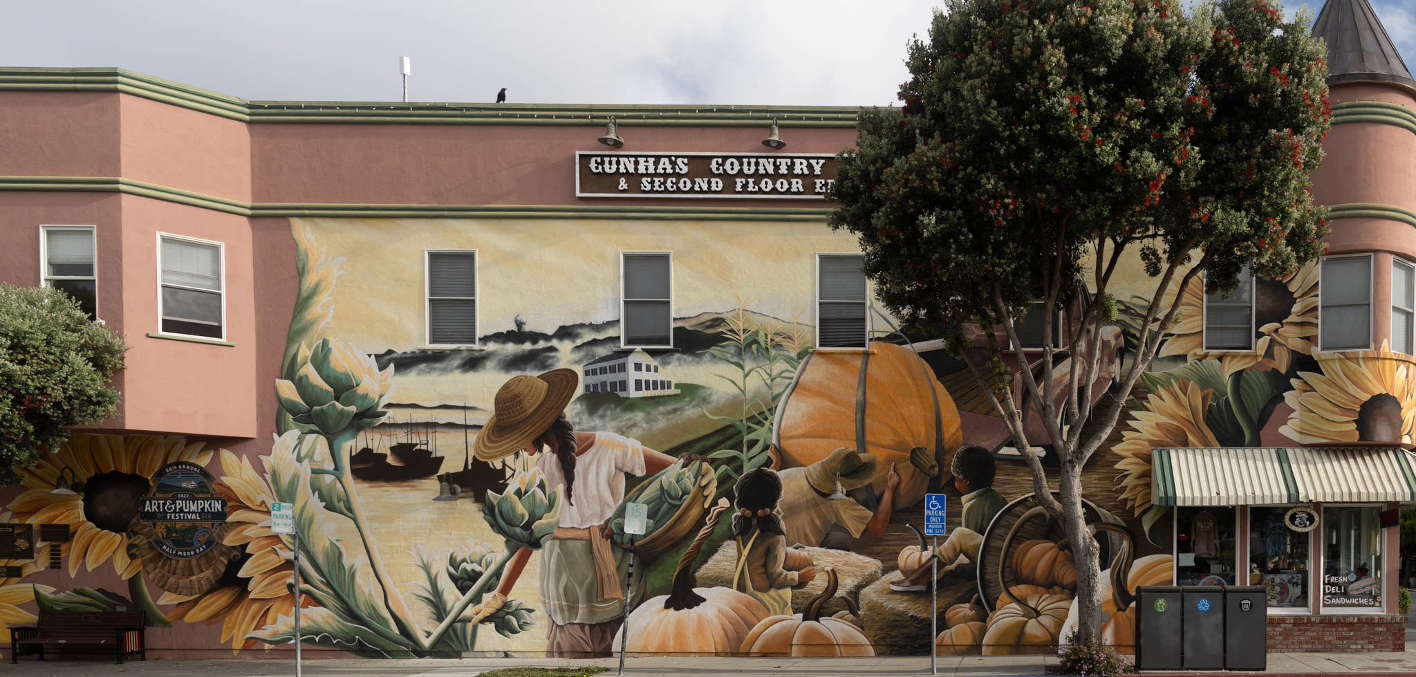 Building facade with a large mural of pumpkins, people, boats, and plants, and a sign reading “FUNHA’S COUNTRY & SECOND FLOOR ET”