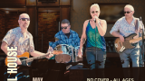 Four musicians performing indoors: a guitarist on the left wearing sunglasses and a patterned shirt, a drummer in the center with sunglasses and a blue plaid shirt, a female vocalist in the center-right with short blonde hair, sunglasses, and a blue-green sleeveless top, and a bassist on the right wearing sunglasses and a patterned shirt. Text includes "American Legion Post 474 Half Moon Bay, CA," "Wheel House," "May 22 Fri 8-10:30PM," "No Cover - All Ages," "Vintage Rock Vibes," and "wheelhousesongs.com." The setting has warm lighting with wood and brick interior elements.