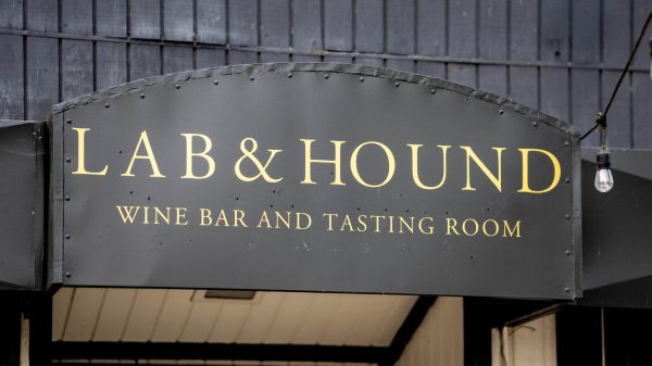 Sign reading “LAB & HOUND” with “WINE BAR AND TASTING ROOM” below, hanging outside a building.