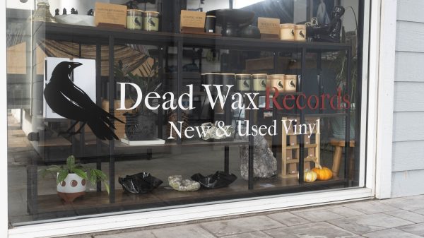Storefront window for Dead Wax Records with a black bird logo and the text “New & Used Vinyl.”