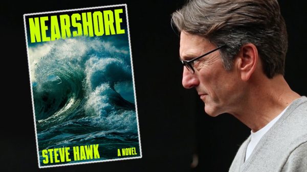 A man with gray hair and glasses, wearing a light gray sweater over a white shirt, is looking intently at a book cover titled "NEARSHORE" by Steve Hawk. The book cover features a large, powerful ocean wave with dark blue and green tones, and the title and author's name are in bold, bright yellow letters. The background behind the man is black.