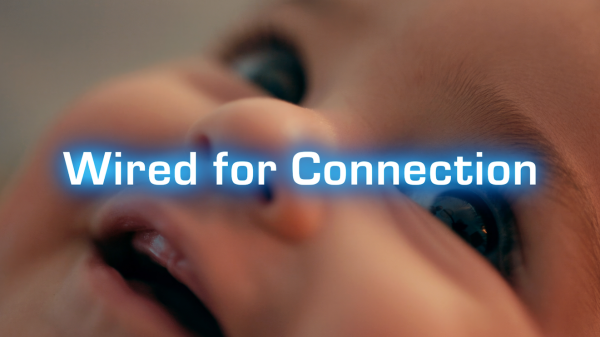 Close-up of a baby's face with a focus on the eyes and mouth, overlaid with the glowing text "Wired for Connection.