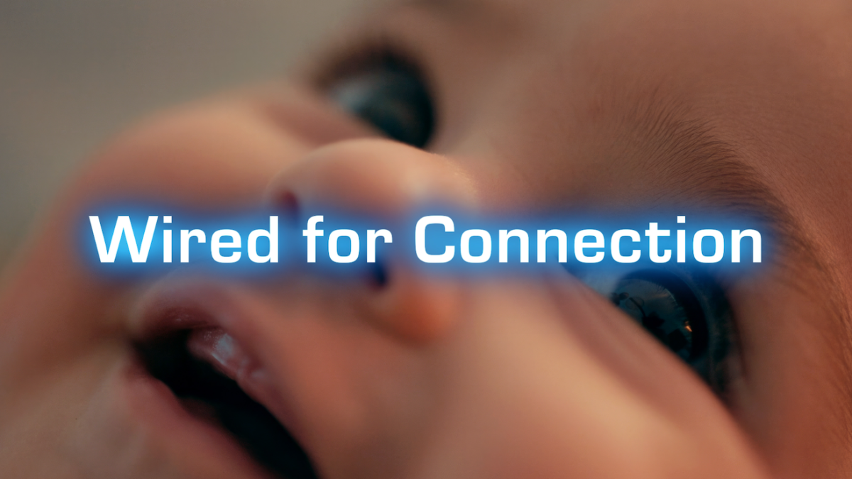 Close-up of a baby's face with a focus on the eyes and mouth, overlaid with the glowing text "Wired for Connection.