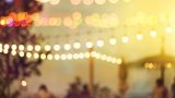 blurred bokeh light on sunset with yellow string lights decor in beach restaurant